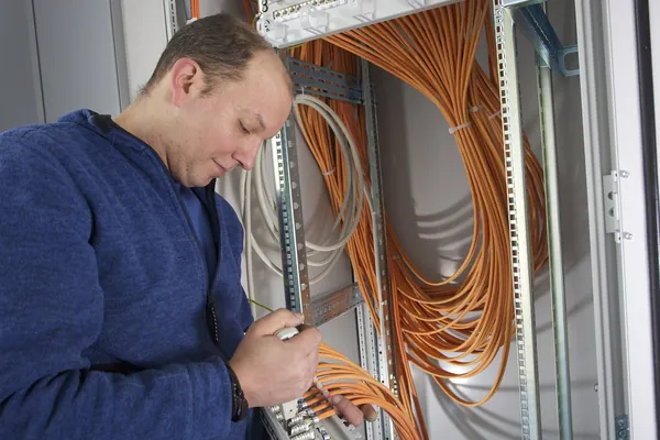 Mitarbeiter montiert ein Patchfeld in einem Netzwerkschrank