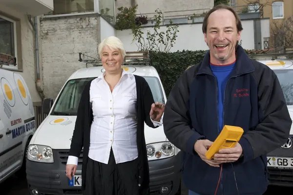 Mitarbeitende mit Prüfgerät vor einem Firmenfahrzeug