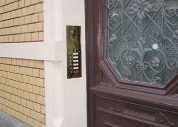 Klingeltableau aus Messing neben einer Haustür aus dunklem Holz